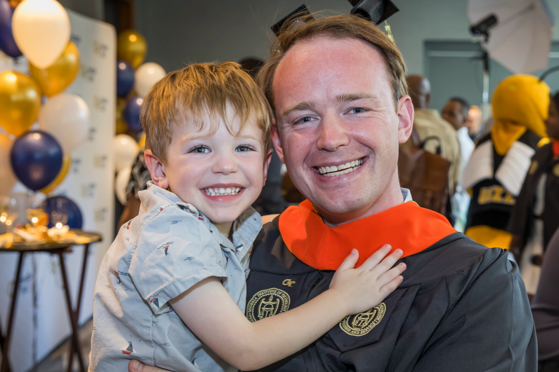 A graduate celebrates commencement with his young son.